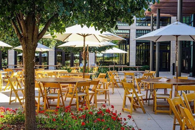 Tische und Stühle draussen unter Sonnenschirmen