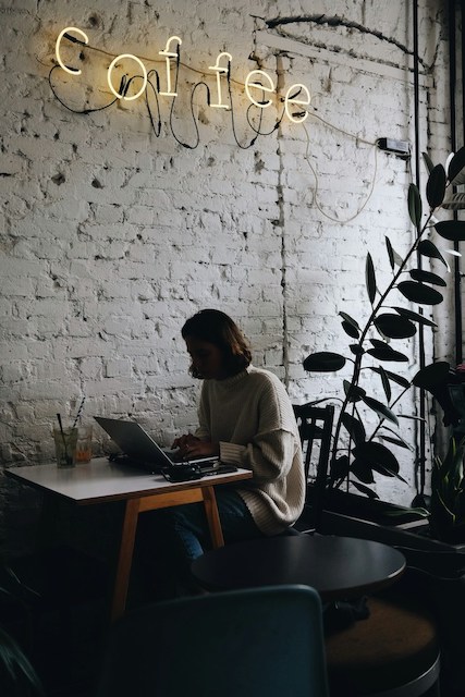 Eine Person die mit einem Laptop an einem Tisch sitzt